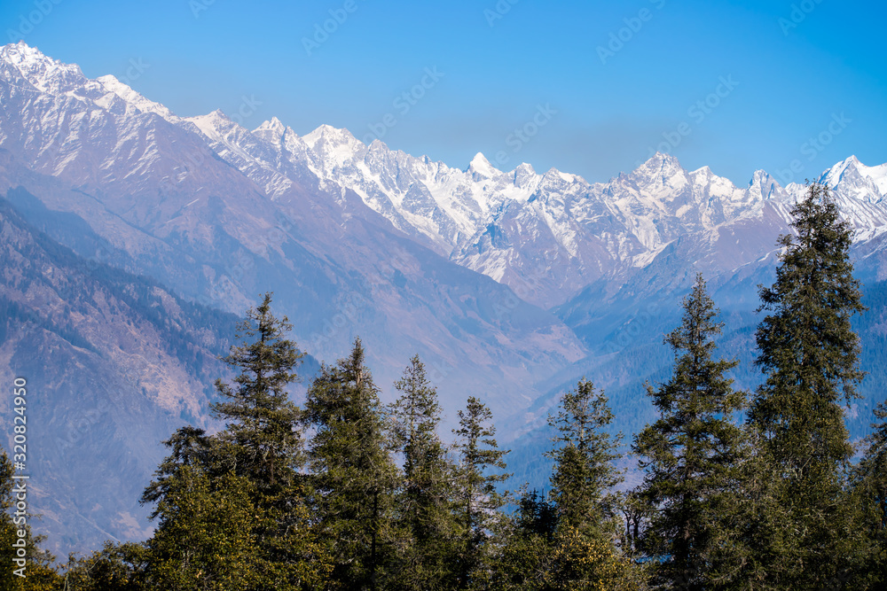 Amazing view of snow clad mountain landscape surrounded by dense forest during Kedarkantha winter trek in Uttarkashi, Uttarakhand (India). Trek in December on Christmas and New Year