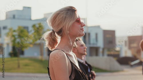 Canvas Print Profile of attractive blonde girl sitting among audience on seats outdoors