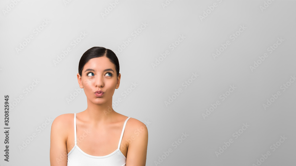 beauty woman with tricky face looking up isolated on grey background with copy space for designs beauty woman with tricky face looking up isolated on grey background with copy space for designs