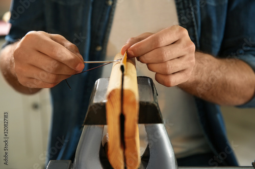 Man sewing piece of leather in workshop, closeup