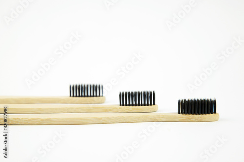 Three bamboo eco toothbrushes with natural bristles lie on a white background. Refusal of plastic. Zero waste. Preservation of the ecology of the planet