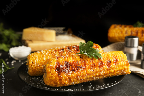 Delicious grilled corn cobs on black table