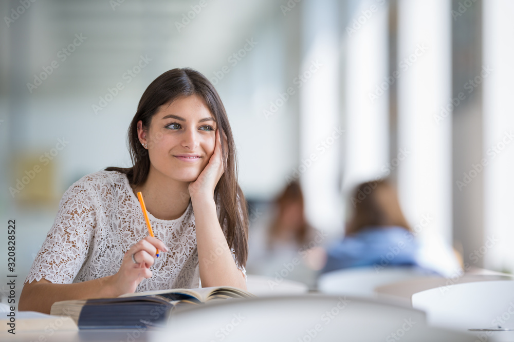 Pretty, young college student looking for a book in the library, studying for her exam Pretty, young college student looking for a book in the library, studying for her exam