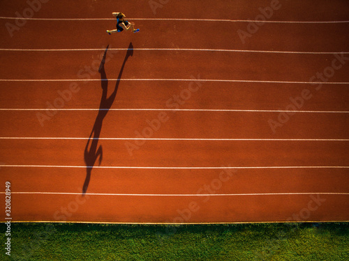 Shot of a young male athlete training on a race track. Sprinter running on athletics tracks seen from above. photo