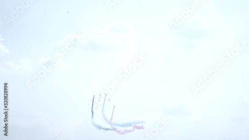 Five fighter jets in the blue sky. Blue, red and white colors. A general plan. Aerobatic figures. Airshow. 10 seconds photo