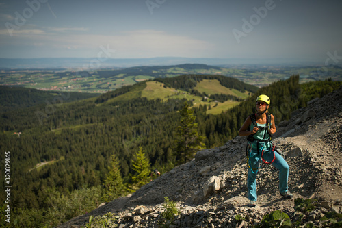Pretty, female climber on a via ferrata - climbing on a rock in Swiss Alps - Approach phase