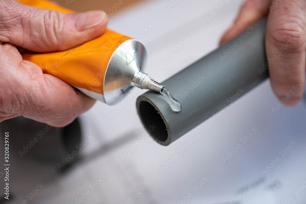 Plumber applying glue on pvc pipe - obrazy, fototapety, plakaty 