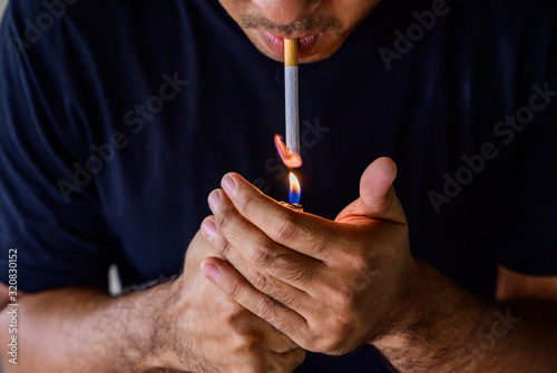 Asian man with stubble lights a cigarette and smokes. Stop smoking concept