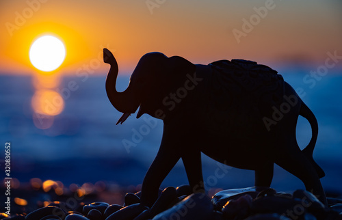 Silhouette of an elephant figurine on the background of the sea and the sunset sky. Balnce, Harmony & Meditation. photo