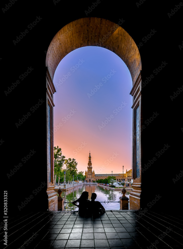 Fototapeta premium Silhouettes of young couple enjoying the sunset in the famous Spain Square (Plaza de Espana). Seville, Spain.