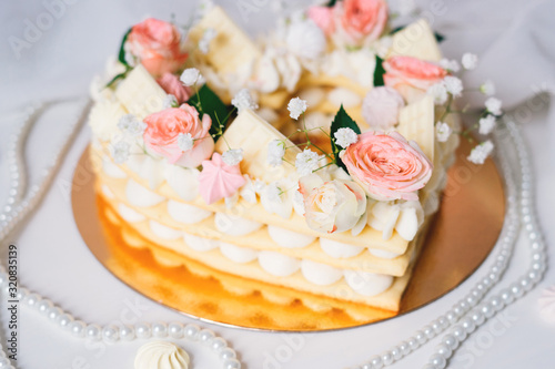 Cake in the form of a heart with cream and flowers.