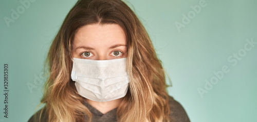 Girl in a medical mask on a green background. Coronavirus. Prevention of viral diseases photo