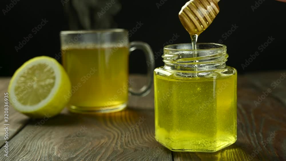 honey flow into jar, background with hot tea and lemon honey flow into jar, background with hot tea and lemon