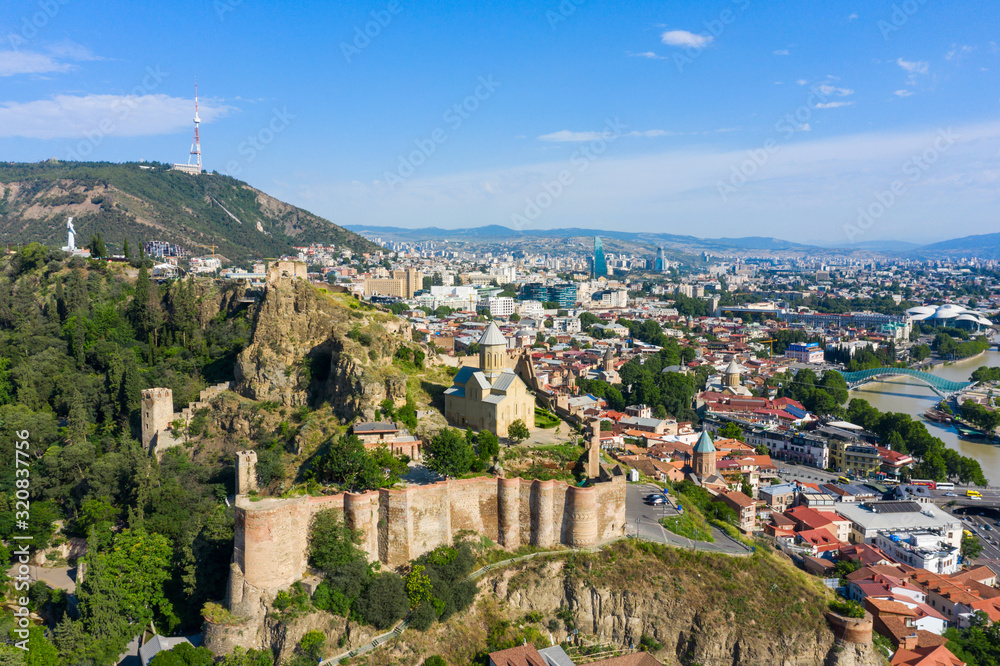 Panorama of the old town on Sololaki hill, crowned with Narikala fortress, the Kura river and cars traffic with blure in Tbilisi, Georgia.