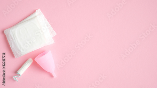 Menstrual hygiene products top view. Flat lay menstrual cup, sanitary pads, tampon on pink background with copy space. Women health care concept.