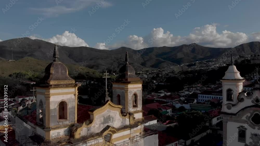 Aerial view of the bell towers of the two churches at central historical Gomes Freire square in the colonial mining town of Mariana in Minas Gerais, Brazil, with rest of the valley in the background Aerial view of the bell towers of the two churches at central historical Gomes Freire square in the colonial mining town of Mariana in Minas Gerais, Brazil, with rest of the valley in the background