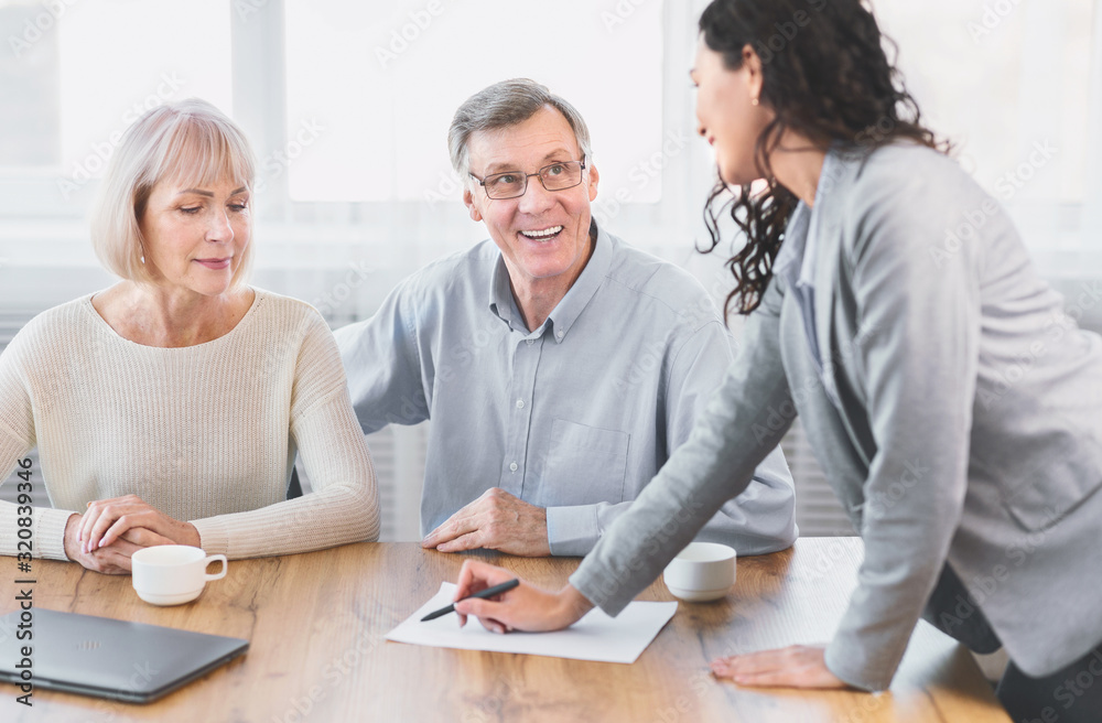 Happy mature couple talking to financial advisor at office Happy mature couple talking to financial advisor at office