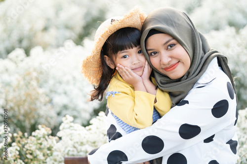 Canvas Print Cute Muslim mother is hugging her lovely daughter with happiness in the garden