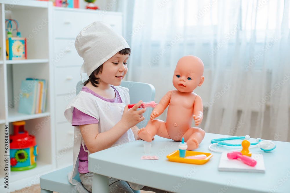 Little girl 3 years old preschooler playing doctor with doll. The child makes an injection toy. Little girl 3 years old preschooler playing doctor with doll. The child makes an injection toy.