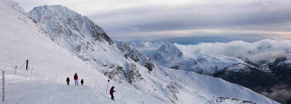 Man Skiing on top of a snow covered mountain during a sunny and cloudy winter day. Taken on Blackcomb mountain, Whistler, British Columbia, Canada.