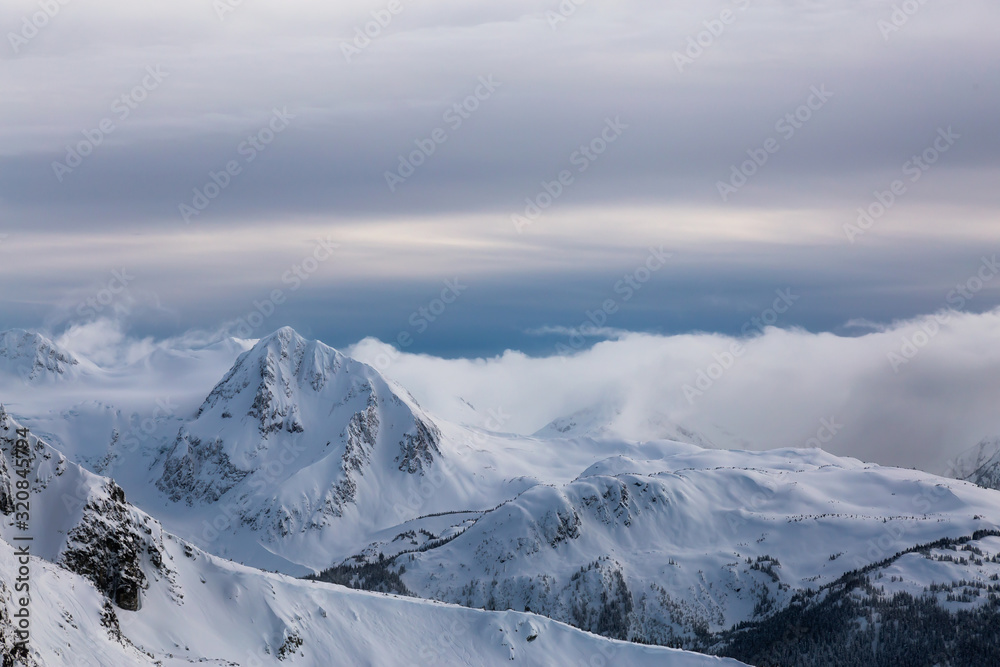 Whistler, British Columbia, Canada. Beautiful Panoramic View of the Canadian Snow Covered Mountain Landscape during a cloudy and vibrant winter sunset.