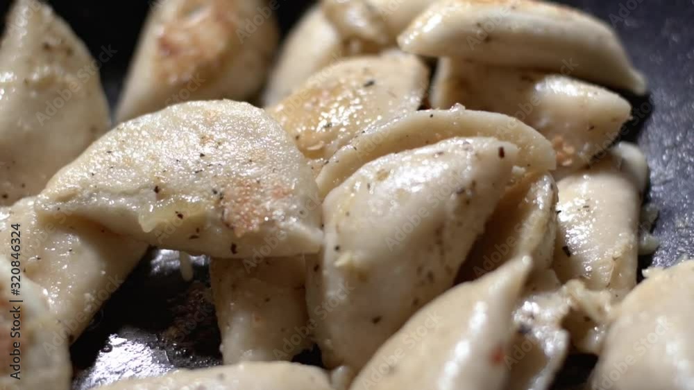 Pierogies flipped over in butter and seasoning In black wok. Pierogies flipped over in butter and seasoning In black wok.