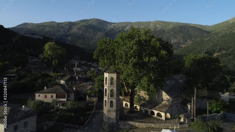 Aerial view circling Papigo village with its traditional stone houses with impressive Tymfi rocky mountain in the background in Zagori, Greece, drone footage Aerial view circling Papigo village with its traditional stone houses with impressive Tymfi rocky mountain in the background in Zagori, Greece, drone footage
