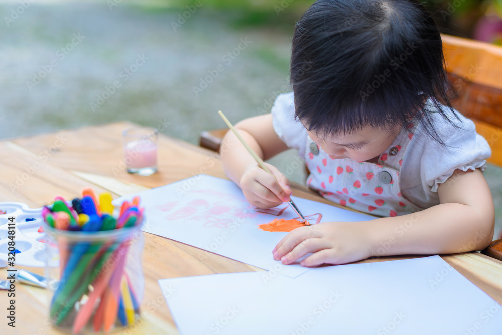 Cute little Asian girl in a white dress is drawing with painting fun Cute little Asian girl in a white dress is drawing with painting fun