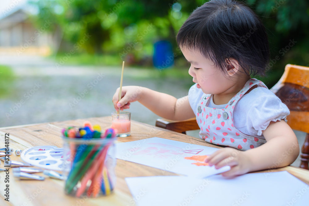 Cute little Asian girl in a white dress is drawing with painting fun Cute little Asian girl in a white dress is drawing with painting fun