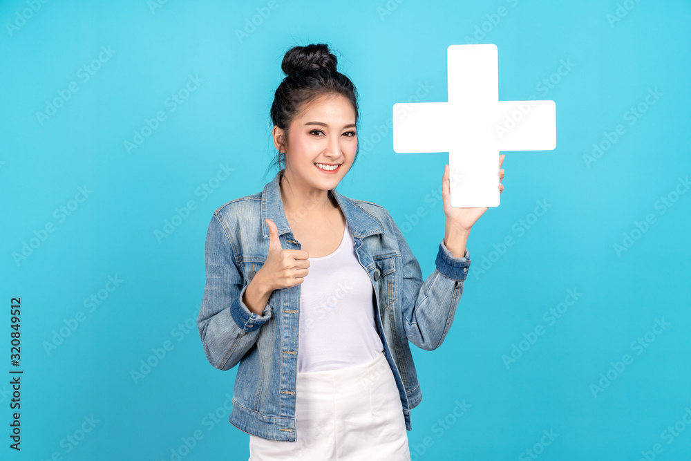 Happiness asian woman smiling, showing plus or add sign and thumb up or like on blue background. Cute asia girl wearing casual jeans shirt and showing join sign for increse and more benefit concept Happiness asian woman smiling, showing plus or add sign and thumb up or like on blue background. Cute asia girl wearing casual jeans shirt and showing join sign for increse and more benefit concept