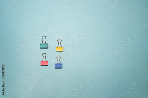 Four binder clips isolated on blue background.