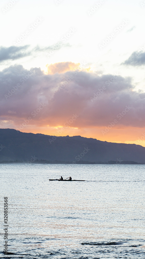 Outrigger canoes at sunset at Haleiwa Hawaii Oahu orange clouds with blank space for copy