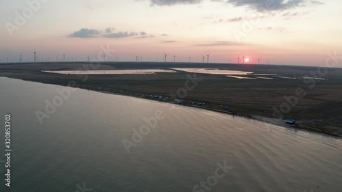 Aerial shot of Azov sea coastline, floodplain, wind tourbine farm on horizon, area of Pryazovskyi national nature park at dusk of setting sun. Drone footage of scenic landscape at sunset, Ukraine photo