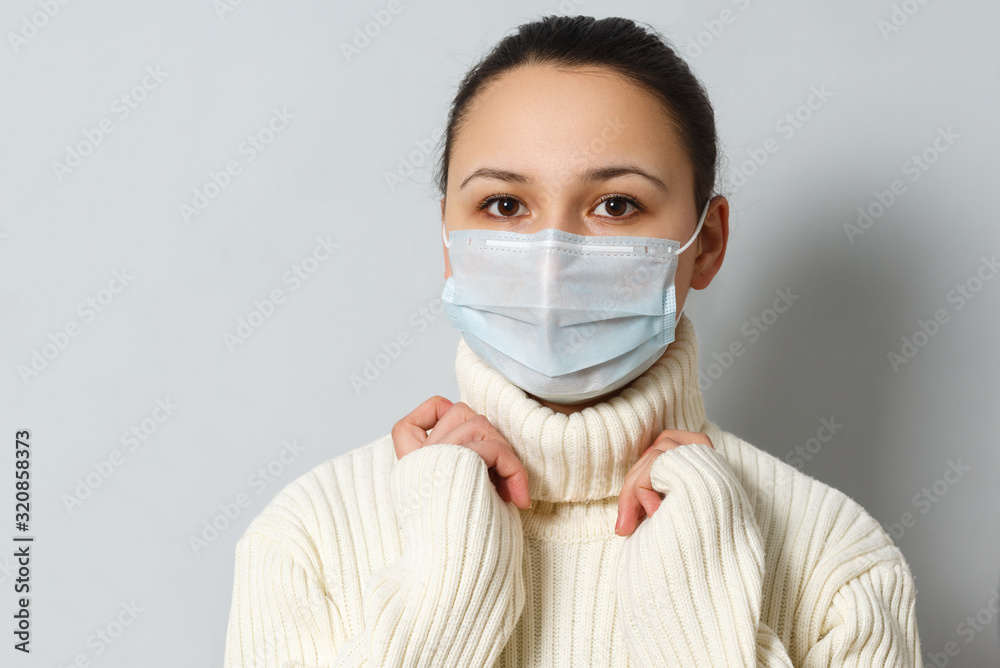 Studio portrait of young woman wearing a face mask, looking at camera, close up, isolated on gray background. Flu epidemic, dust allergy, protection against virus Studio portrait of young woman wearing a face mask, looking at camera, close up, isolated on gray background. Flu epidemic, dust allergy, protection against virus