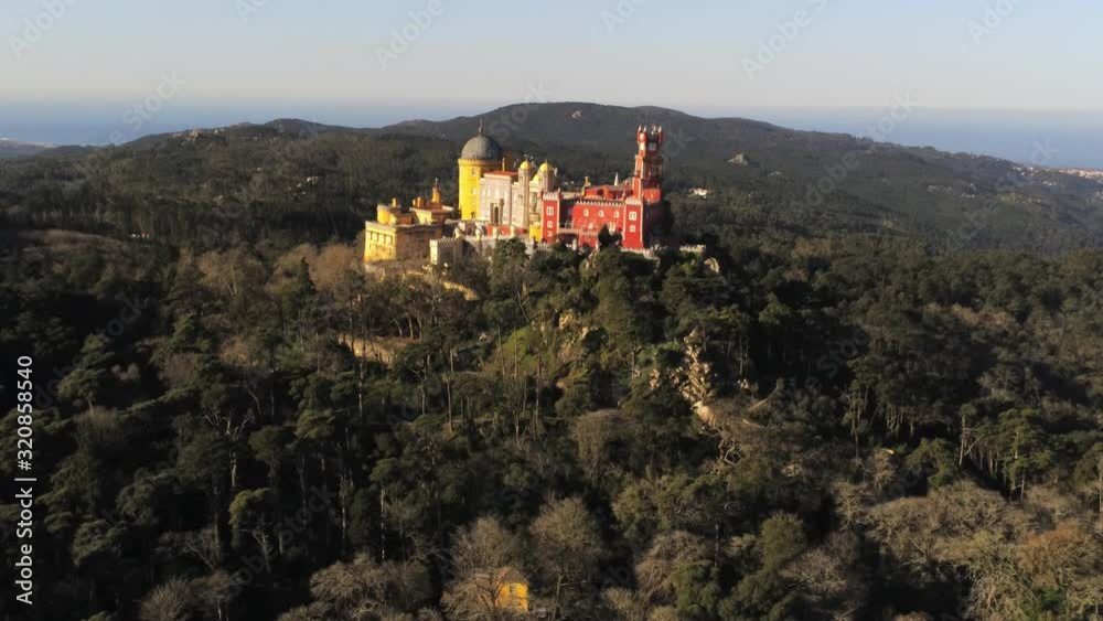 Beautiful aerial drone view of Romanesque Pena Palace's fairy tale atmosphere in the middle of forest with it's amazing colors during sunset Beautiful aerial drone view of Romanesque Pena Palace's fairy tale atmosphere in the middle of forest with it's amazing colors during sunset