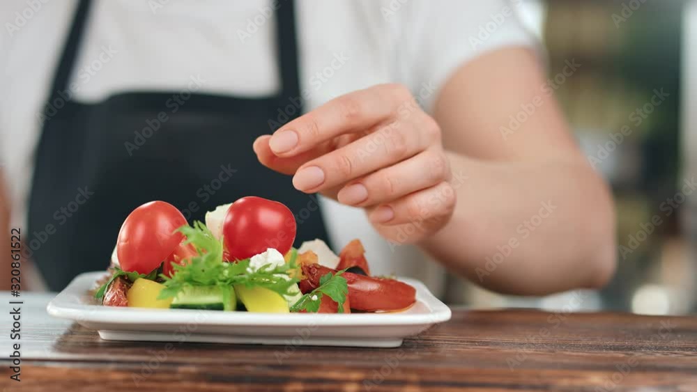 Close up female hand in apron adding fresh tomato to vegetable mix. Wide shot on RED camera Close up female hand in apron adding fresh tomato to vegetable mix. Wide shot on RED camera