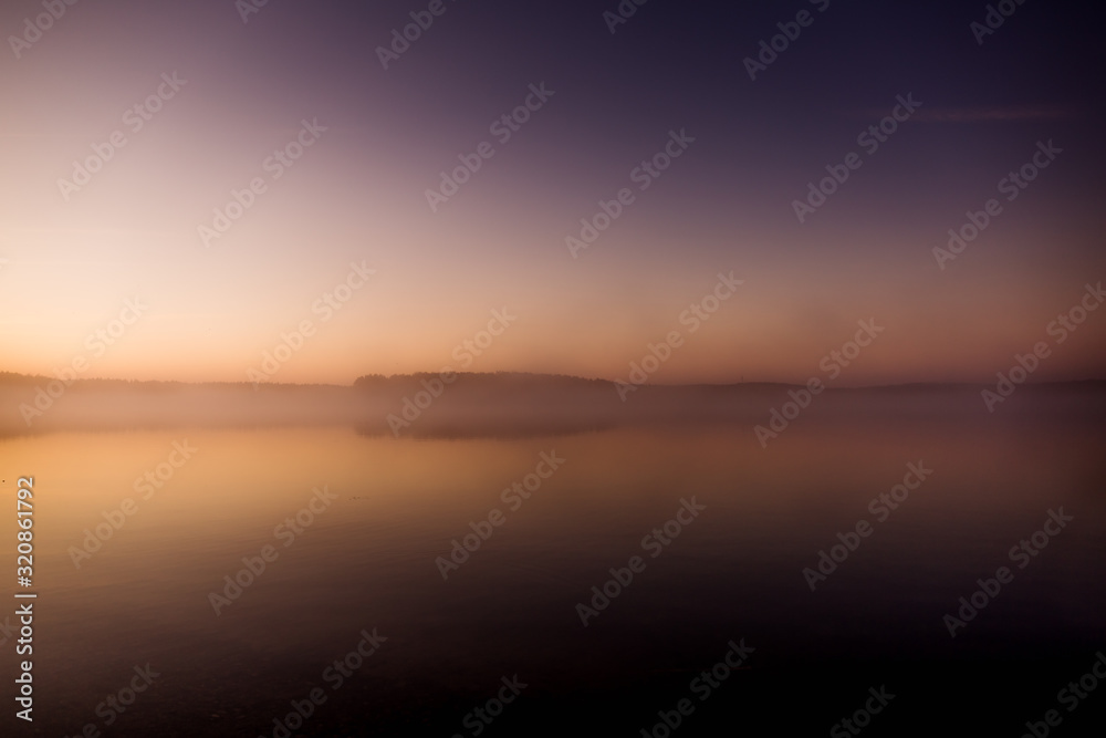 Early morning on the lake with a pink dawn and shrouded haze of mist, a mesmerizing mysticism of nature