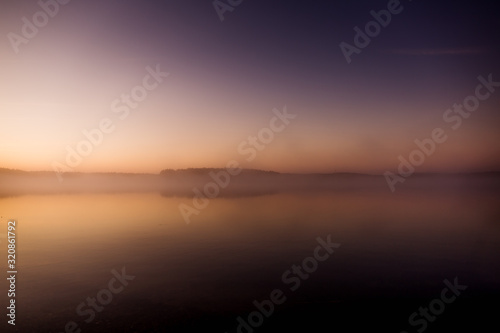 Early morning on the lake with a pink dawn and shrouded haze of mist  a mesmerizing mysticism of nature