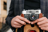 Close-up photo of man with brown skin standing on the street after photoshoot. Outdoor portrait of male hands holding camera.