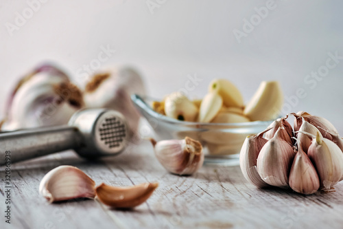 Garlic Cloves and Bulb in wooden bowl on white table.