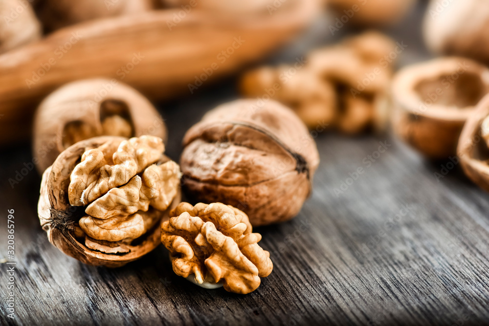 Whole walnuts on dark board, Walnut kernels in wood rustic bowl. Whole walnuts on dark board, Walnut kernels in wood rustic bowl.