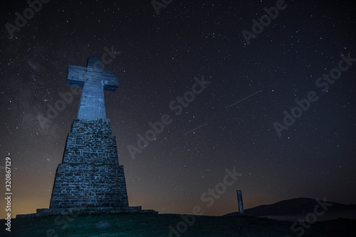 cross in a mountain summit under the stars, basque country