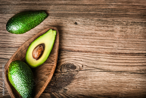 Avocado on old wooden table. Halfs of avocados at wood board. Fresh fruits healthy food. copy space for text.