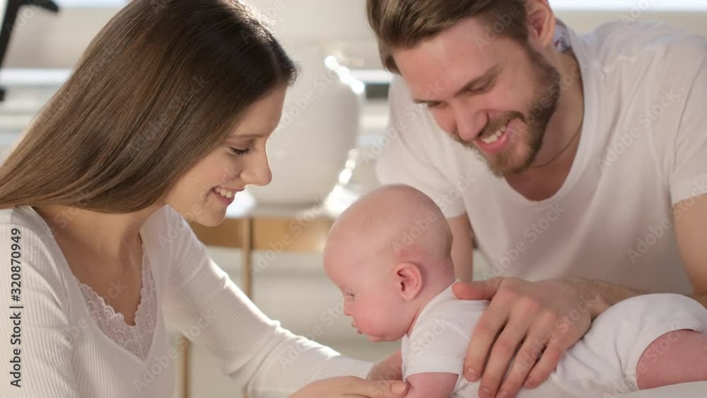 Happy family. Portrait of caucasian smiling mother father and newborn baby hugging at home. Parenthood Motherhood. Loving parents mom dad enjoying caring little child. healthy childcare, 4 K Slow-mo Happy family. Portrait of caucasian smiling mother father and newborn baby hugging at home. Parenthood Motherhood. Loving parents mom dad enjoying caring little child. healthy childcare, 4 K Slow-mo