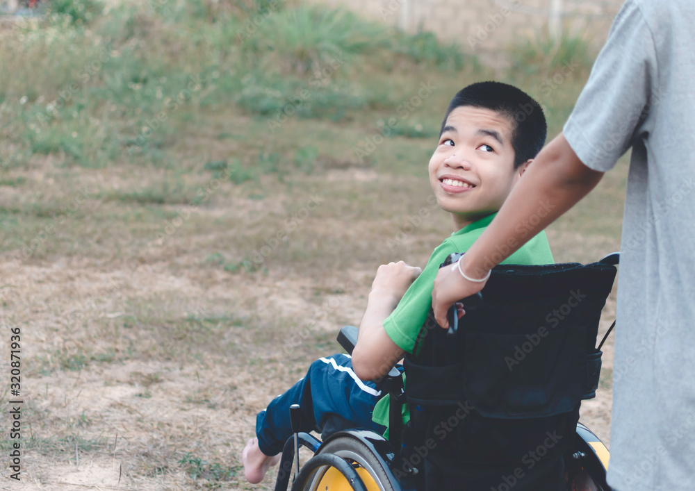 Portrait of Disabled child on wheelchair and freind's hand,Grass field ...