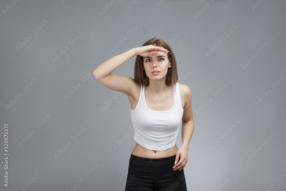 Woman looking far away with hand above her eyes Woman looking far away with hand above her eyes