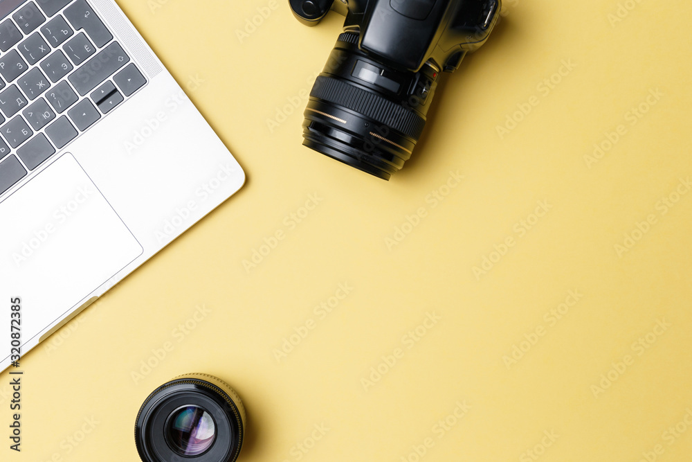 Photographer's workplace on a yellow background. Modern laptop, digital camera, lens, battery, smartphone. Minimalism. Top view. Copy space. Equipment for the photographer. The concept of freelancing