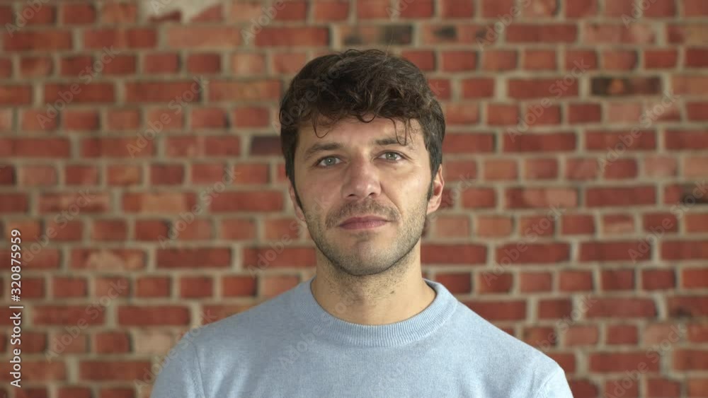 Suggestive portrait of handsome young man with blue sweater rising the head, looking at camera and smiling. Happy sensual attractive bearded guy. Suggestive portrait of handsome young man with blue sweater rising the head, looking at camera and smiling. Happy sensual attractive bearded guy.