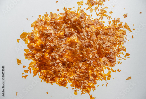 Shellac flakes, shellac is a  resin secreted by the female lac bug. It is dissolved in alcohol to make liquid shellac, which is used as a brush-on colorant, food glaze and wood finish. photo