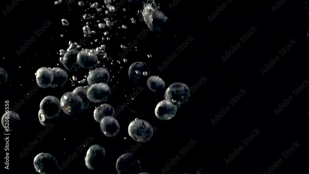 Studio shot of sweet blueberries dropping into the water in slow motion. Cleaning fresh black berries in the water. Fresh fruits and healthy eating concept. Studio shot of sweet blueberries dropping into the water in slow motion. Cleaning fresh black berries in the water. Fresh fruits and healthy eating concept.